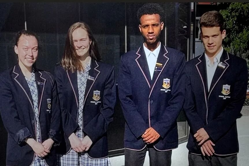 Two young women stand next to two young men in school uniforms.
